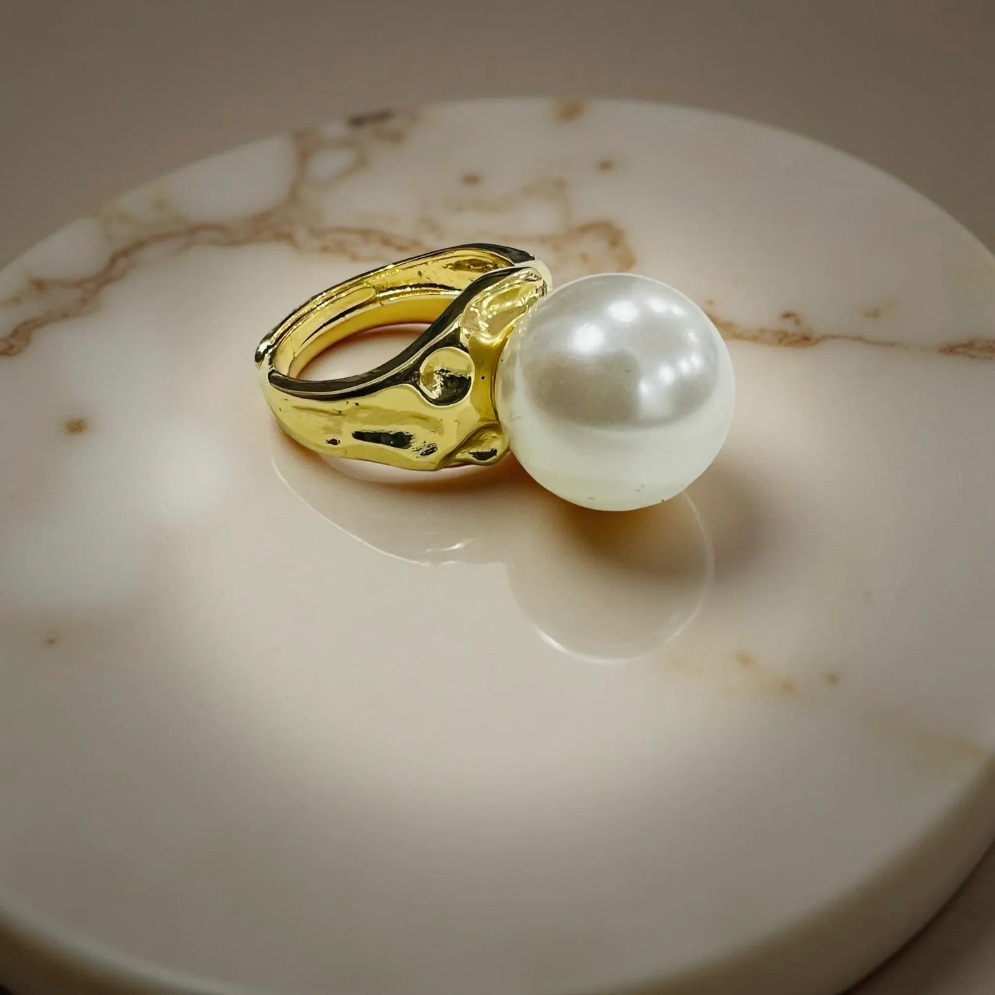 Gold-plated statement pearl ring by Jinam featuring a large central pearl and elegant gold band.