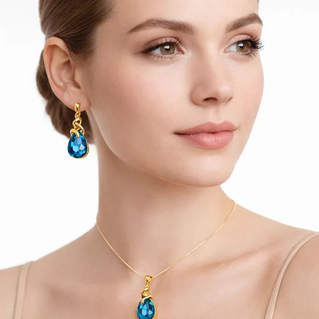 Gold-plated blue tear-drop stone pendant jewelry set by Jinam, featuring matching earrings and necklace on a white background.