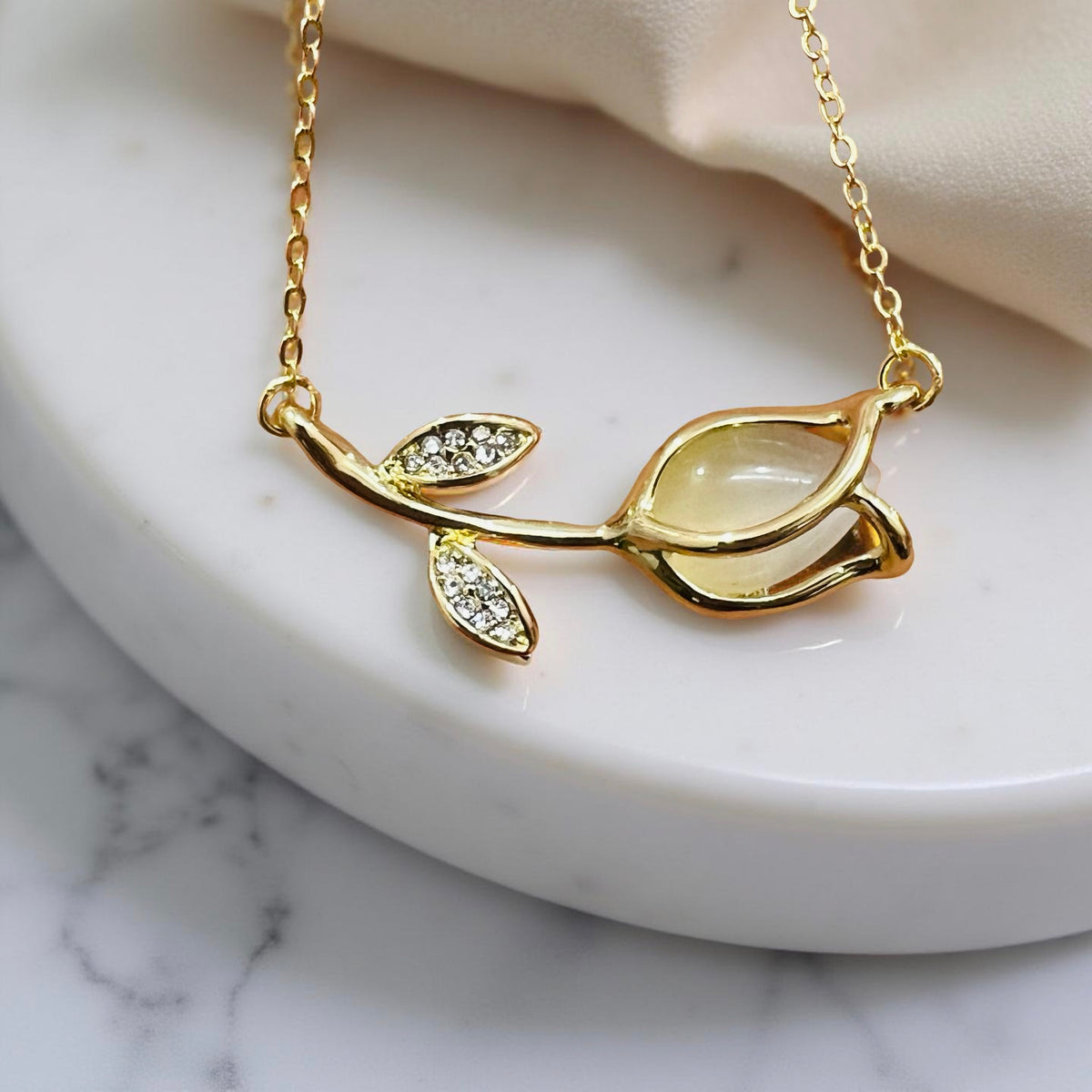 Gold-plated floral bud pendant and earrings set by Jinam, featuring delicate flower designs on a chain and matching dangle earrings.
