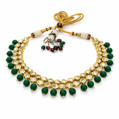 Elegant emerald and kundan imitation necklace set by Jinam featuring intricate gold-tone detailing and matching earrings.